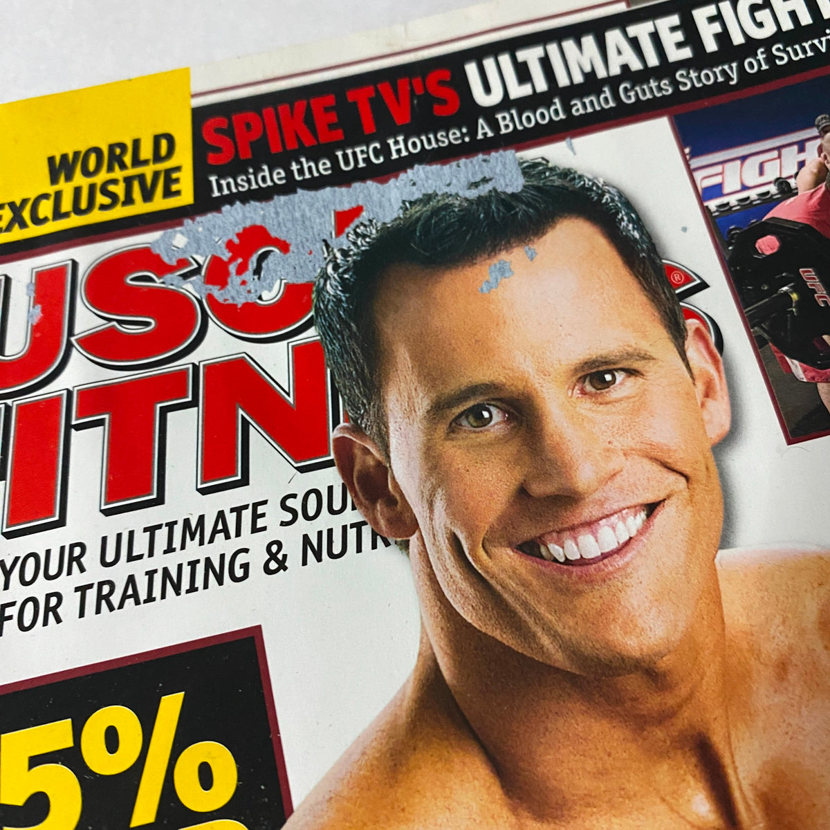 Close-up of the top portion of Muscle & Fitness Magazine December 2008 highlighting a smiling fitness model and promotional text.