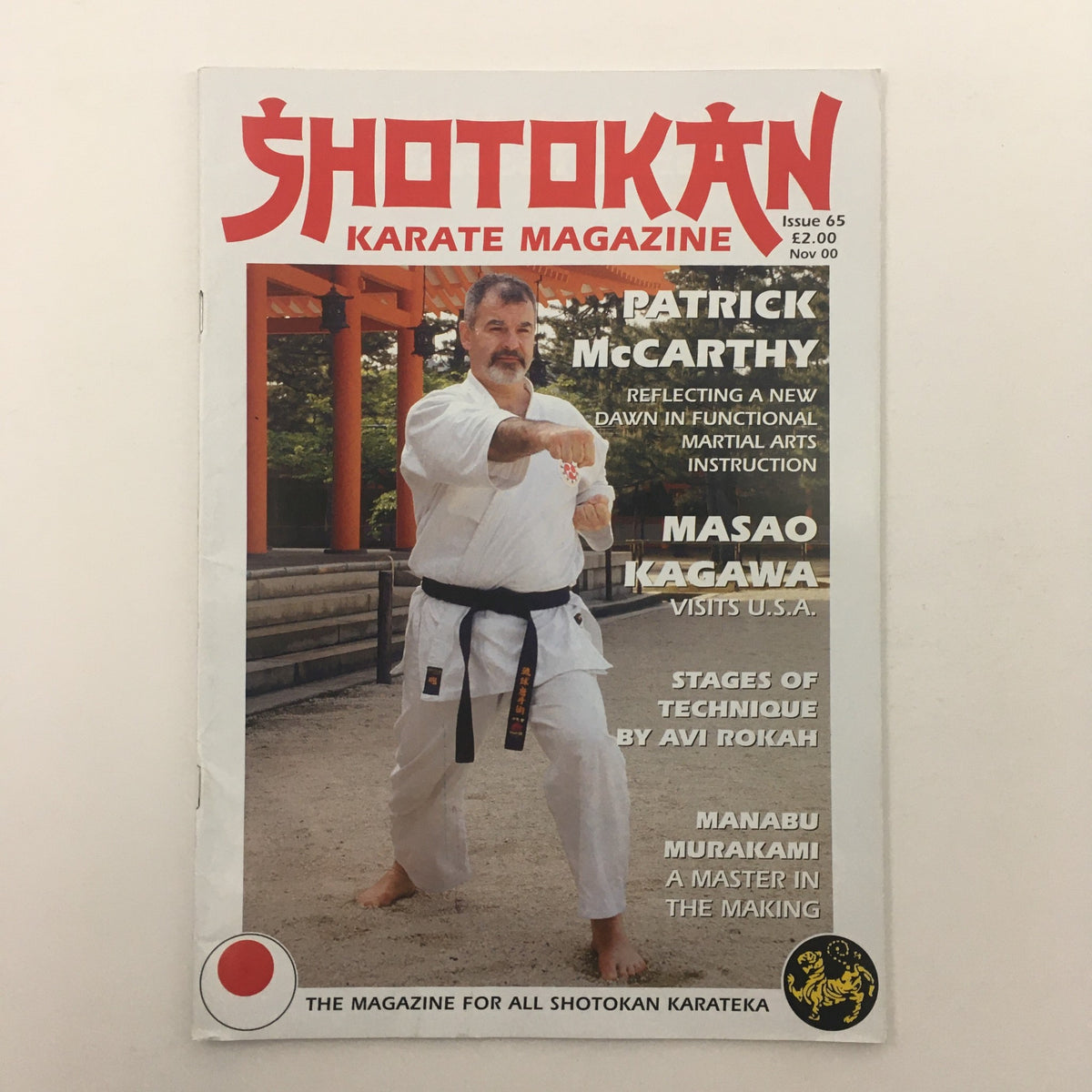 Cover of Shotokan Karate Magazine November 2000 issue #65 featuring Master Patrick McCarthy demonstrating martial arts techniques, alongside a silhouette of the Shotokan logo, emphasizing its significance for karate enthusiasts and collectors.