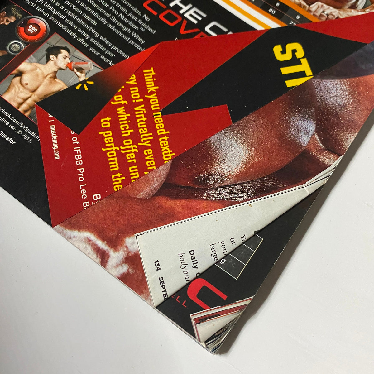 Page from MuscleMag Magazine September 2011 No. 352 showing creased edges and graphics related to bodybuilding products.