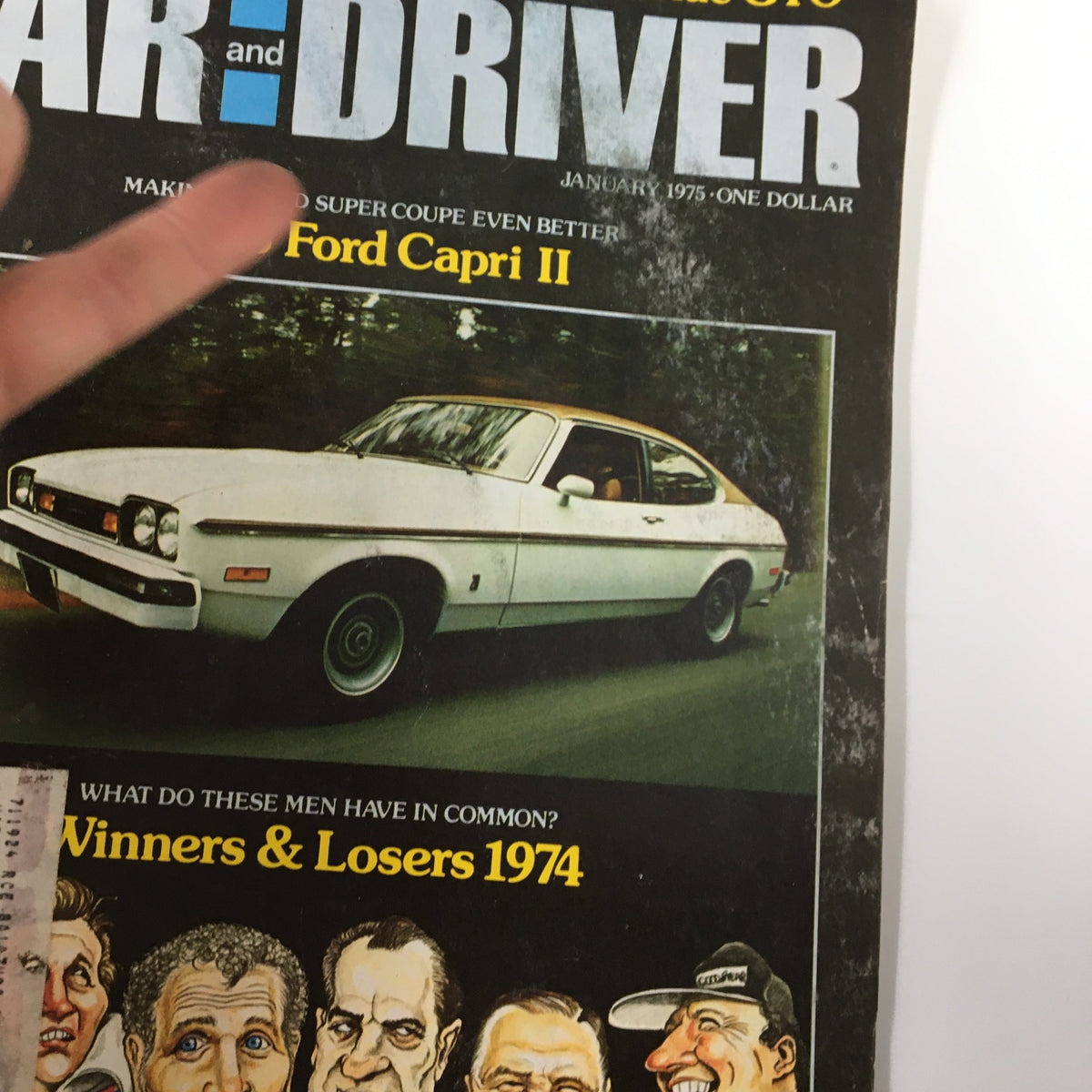 Close-up view of the VTG Car and Driver Magazine January 1975 cover showcasing a Ford Capri II and caricatures referencing 1974's notable figures.
