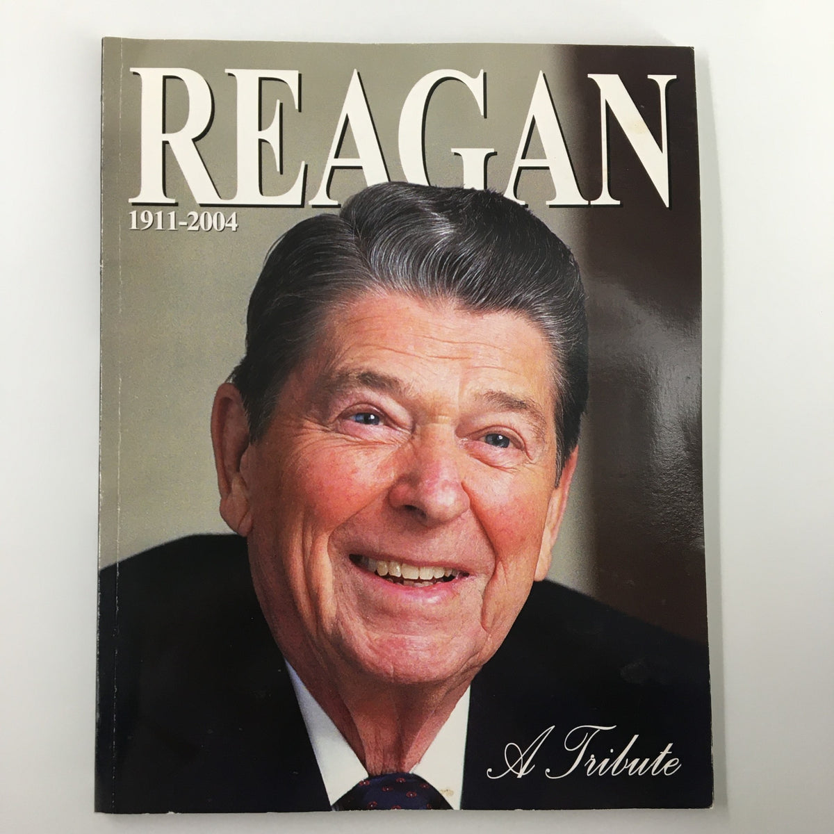 Cover of 'A Tribute To Reagan 1911 - 2004', featuring a smiling Ronald Reagan with gray hair, representing his legacy as a significant U.S. President.
