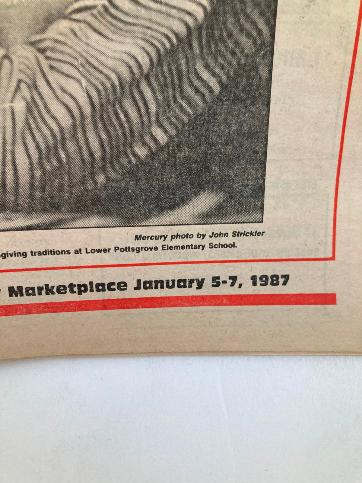 A close-up image from 'The Mercury Supplementary Tabloid January 5, 1987 Chronology '86 Time to Reflect', showing a photograph by John Strickler of LLower Pottsgrove Elementary School along with a date reference for the Marketplace event.