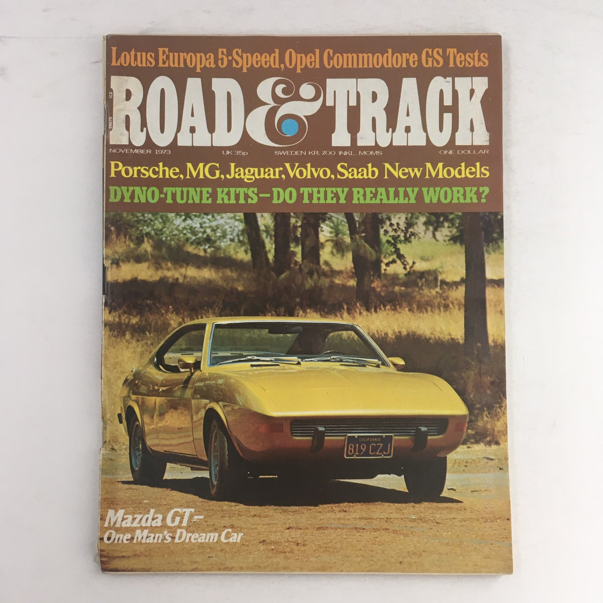 Cover of Road & Track Magazine November 1973 featuring Mazda GT, Porsche, MG, Jaguar, and Saab new models, showcasing automotive history and innovations from the early 1970s.