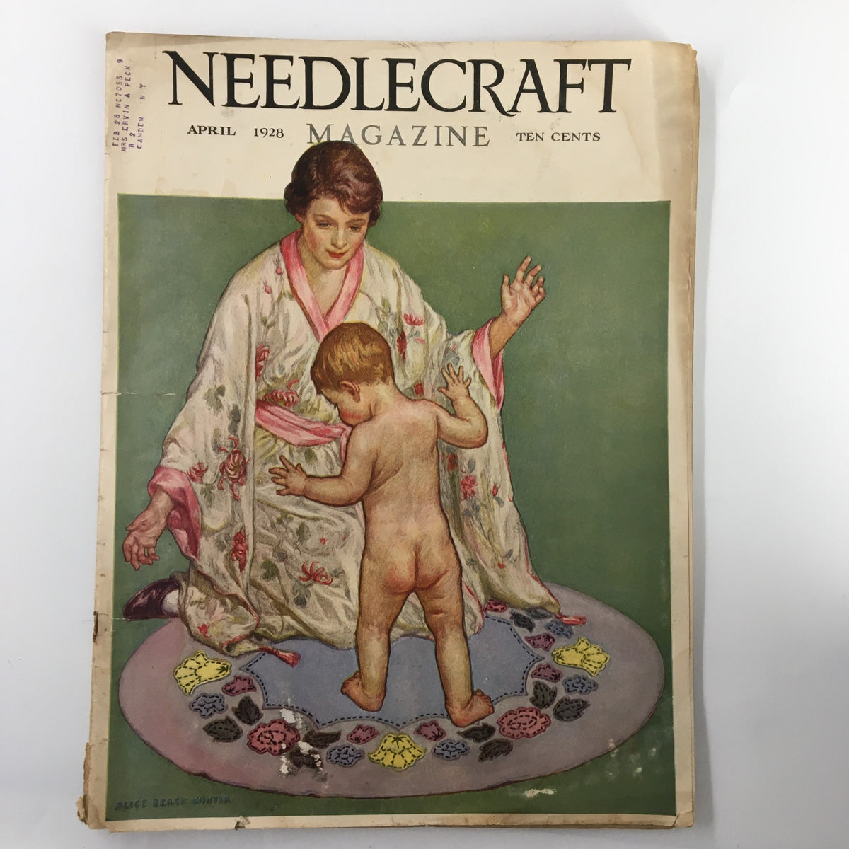VTG Needlecraft Magazine April 1928, featuring a colorful cover illustration of a woman in a floral robe interacting with a child on a patterned floor mat. This vintage magazine is a collector's gem for needlework enthusiasts.