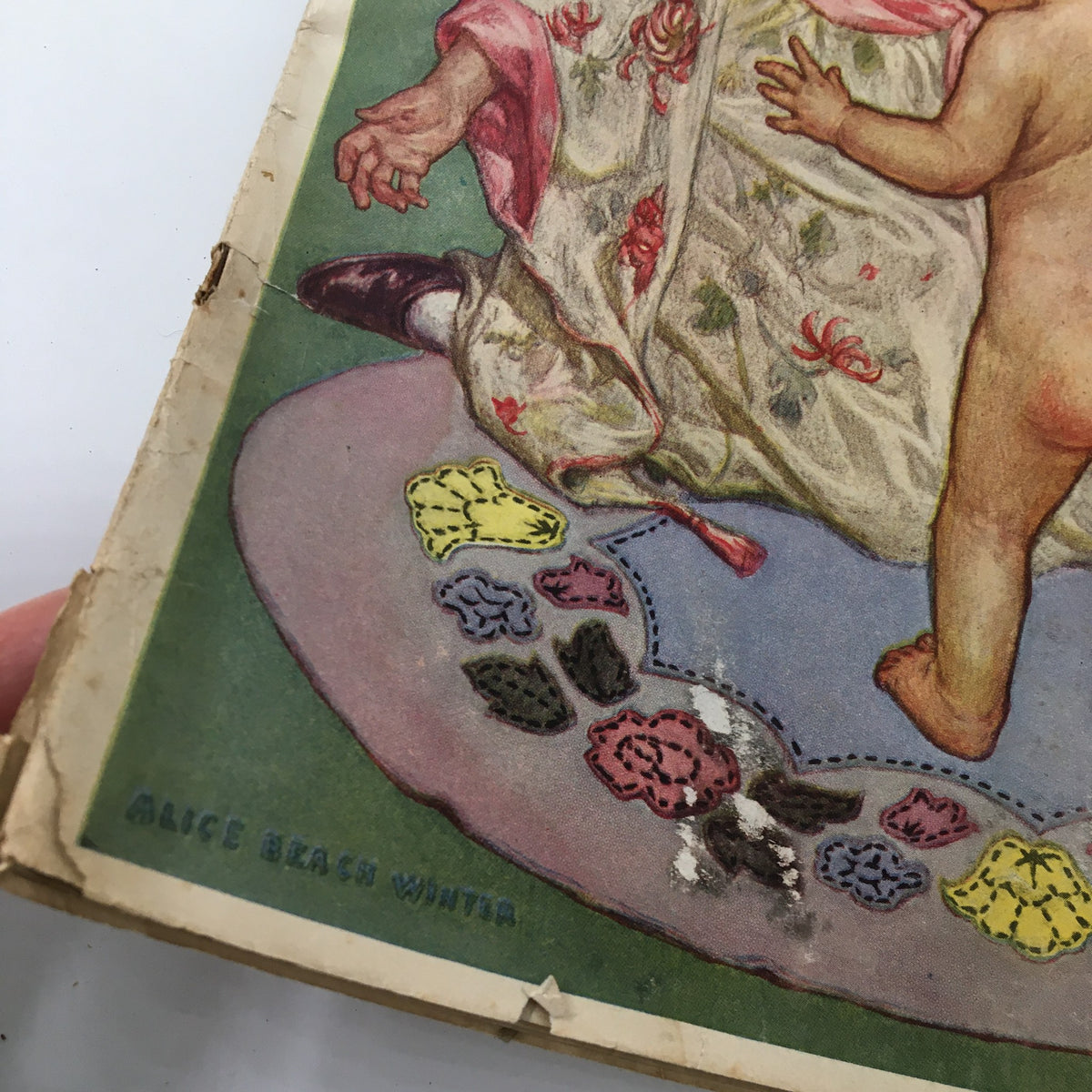 Close-up of the VTG Needlecraft Magazine April 1928 cover, highlighting the intricate details of the artwork by Alice Beach Winter, showcasing a woman and child on a decorative mat, perfect for vintage needlecraft collectors.