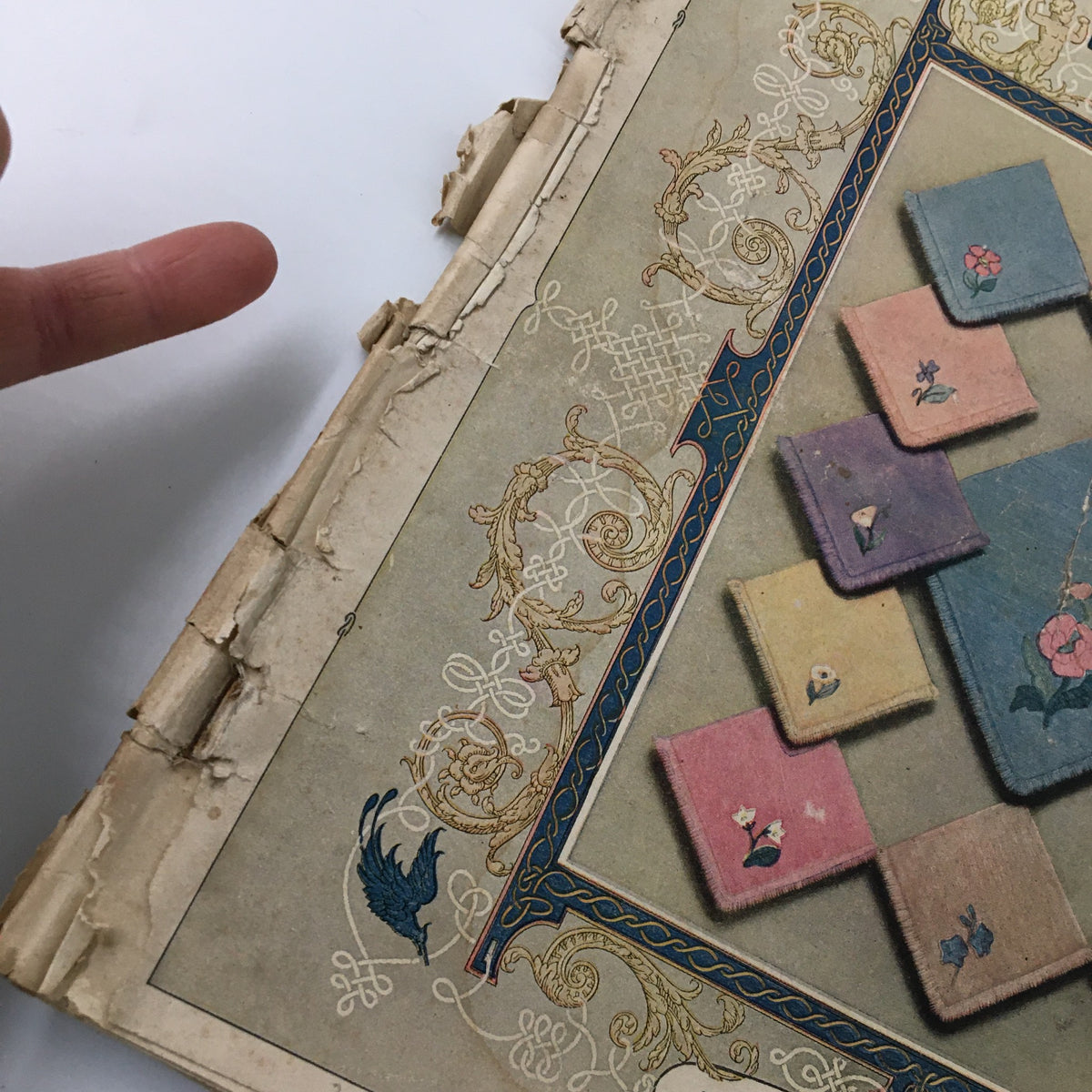 Close-up of damaged edge of VTG Needlecraft Magazine December 1924 Vol. 16 No. 4, showcasing the vintage cover design detail.
