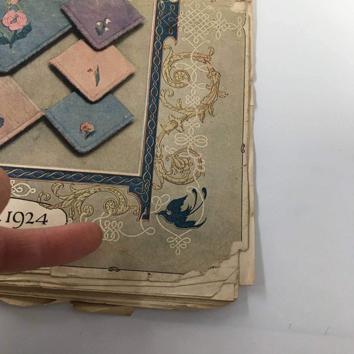 Side view of the VTG Needlecraft Magazine December 1924 Vol. 16 No. 4, highlighting its worn edges and artistic cover layout.