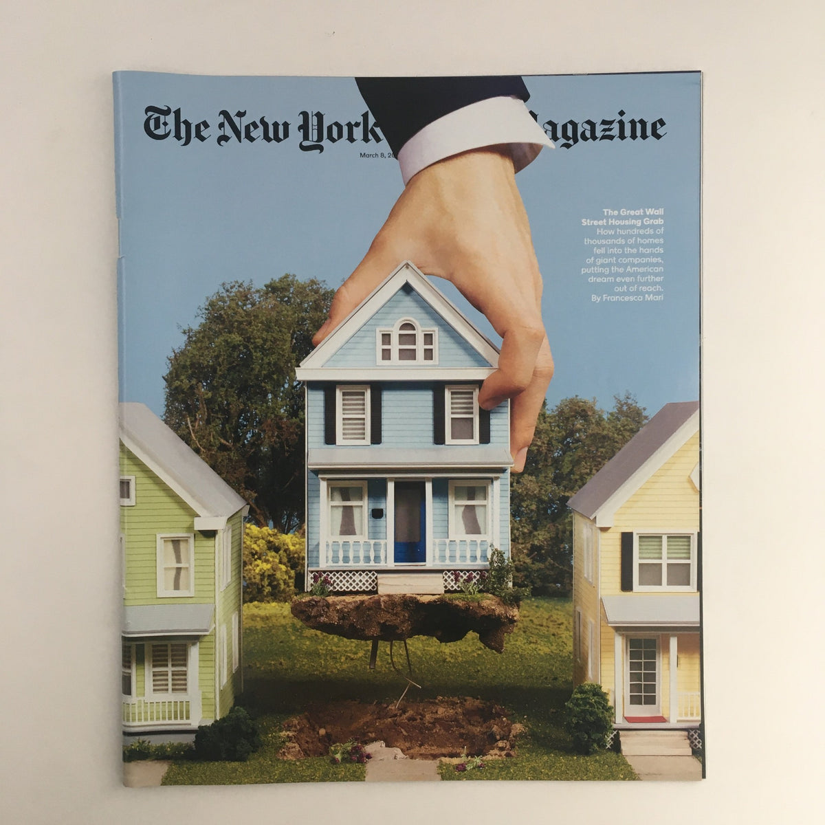 Cover of The New York Times Magazine from March 8, 2020, featuring the article 'The Great Wall Street Grab'. The image shows a surreal depiction of a house being held by a hand, set between two colorful houses, symbolizing the intersection of finance and home ownership.
