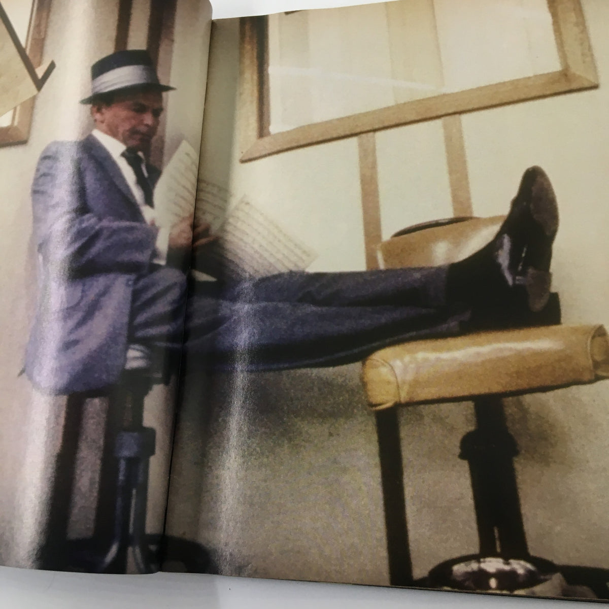 Frank Sinatra relaxing while reading music sheets, featured in Luxury Lifestyles Magazine 1998, highlighting his artistic lifestyle.