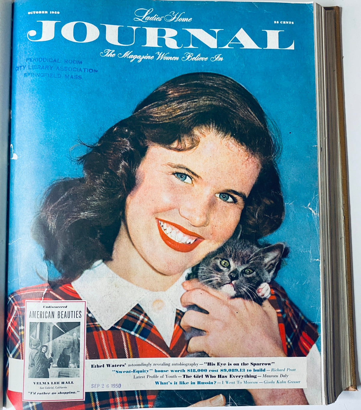 Ladies' Home Journal magazine cover from October 1950 featuring a smiling woman holding a kitten. This image highlights the charm of the 1950s with a vibrant blue backdrop and a nostalgic design.