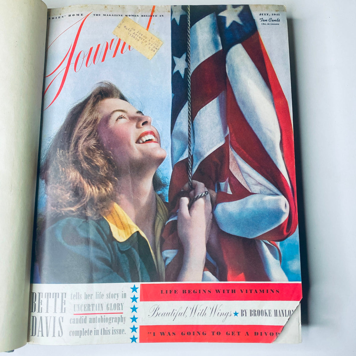 Cover of Ladies' Home Journal July 1941 featuring a woman smiling while holding an American flag. Part of the 1941 full year collection of the magazine.