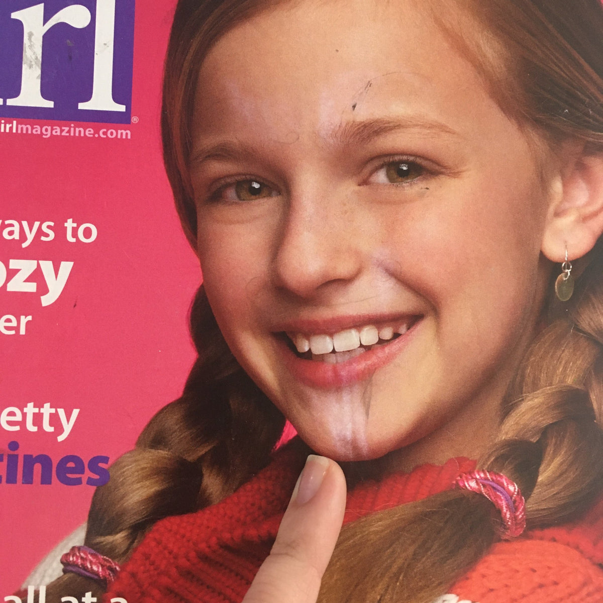 Close-up of the smiling girl on the cover of American Girl Magazine January 2011, showing details of her joyful expression and colorful sweater. This issue highlights '10 ways to be cozy this winter.'
