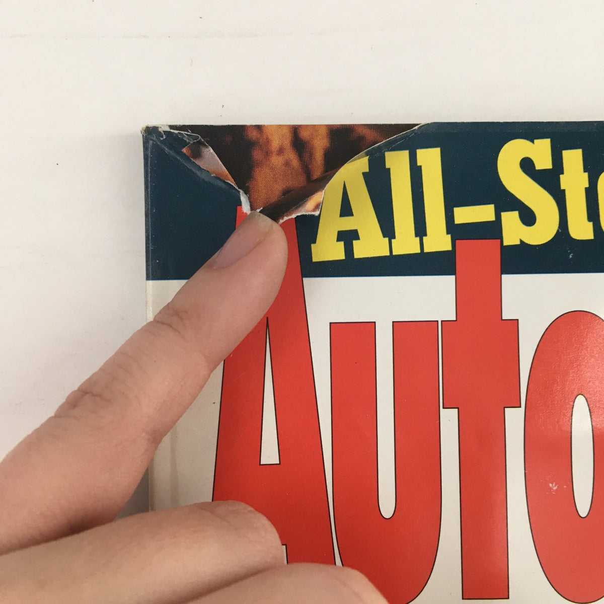 Close-up view of the damaged corner of the February 1996 issue of Automobile Magazine, showing the title 'Automobile' with a visible rip, emphasizing the magazine's condition as a collectible piece.