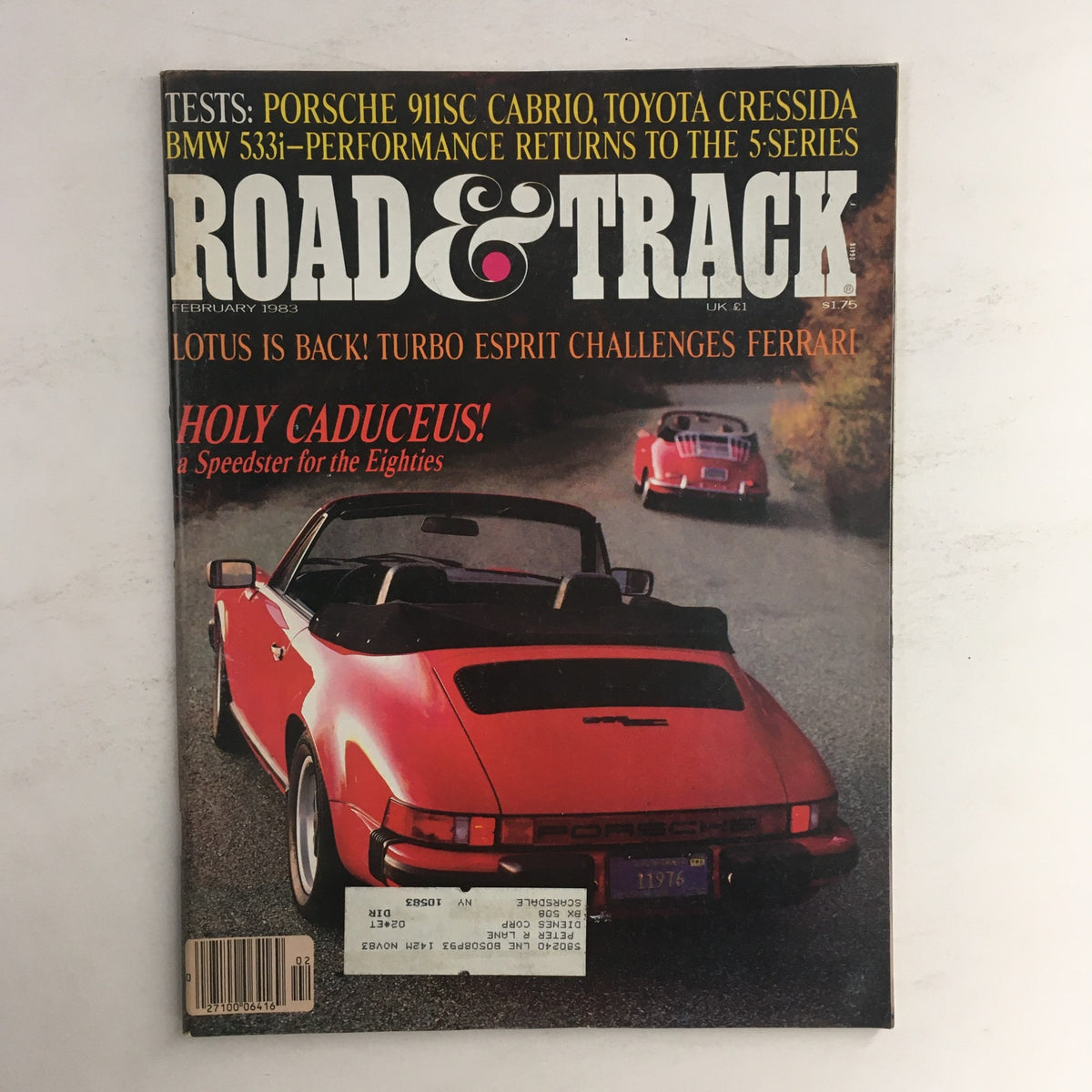 Cover of Road & Track Magazine, February 1983 issue featuring tests of the Porsche 911SC Cabrio and Toyota Cressida. The magazine shows a red Porsche 911SC Cabriolet on a scenic driving path, highlighting vintage automotive design.