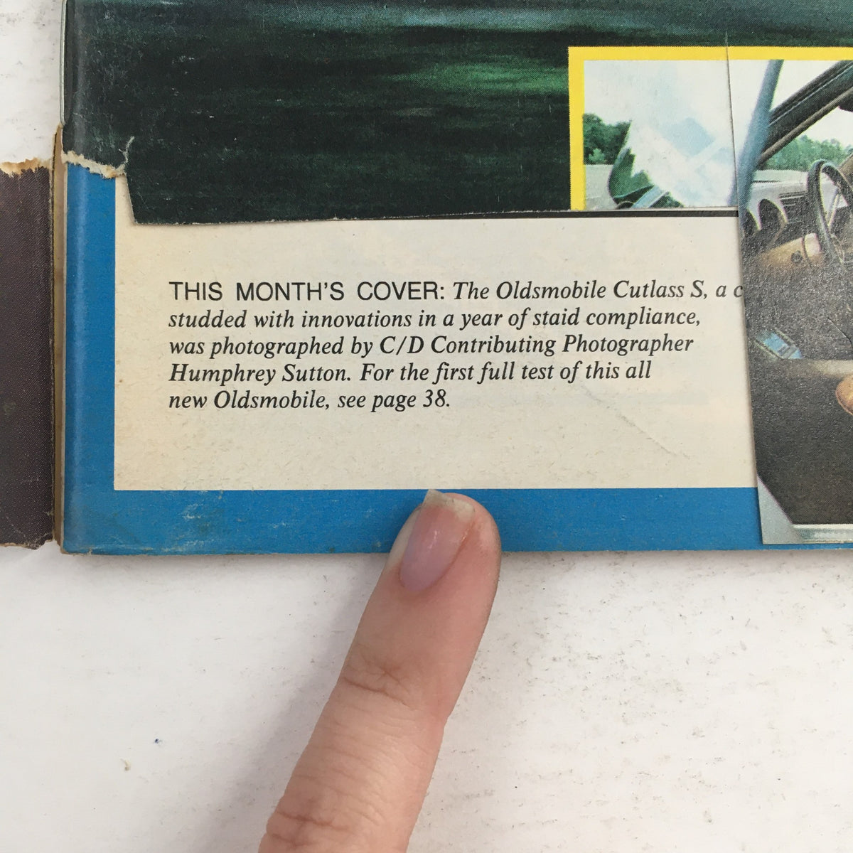 Back cover of Car and Driver Magazine November 1972 featuring a description of the Oldsmobile Cutlass S, with a finger pointing at the text, highlighting automotive innovations from that era.