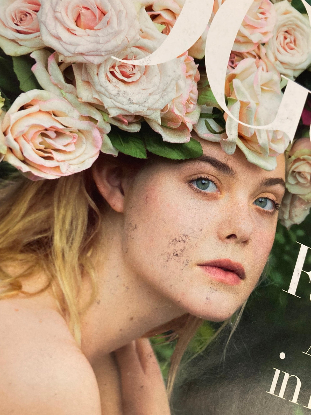 Close-up of Elle Fanning on the cover of Vogue Magazine June 2017, highlighting her captivating blue eyes and floral headpiece, representing A Star in Bloom.