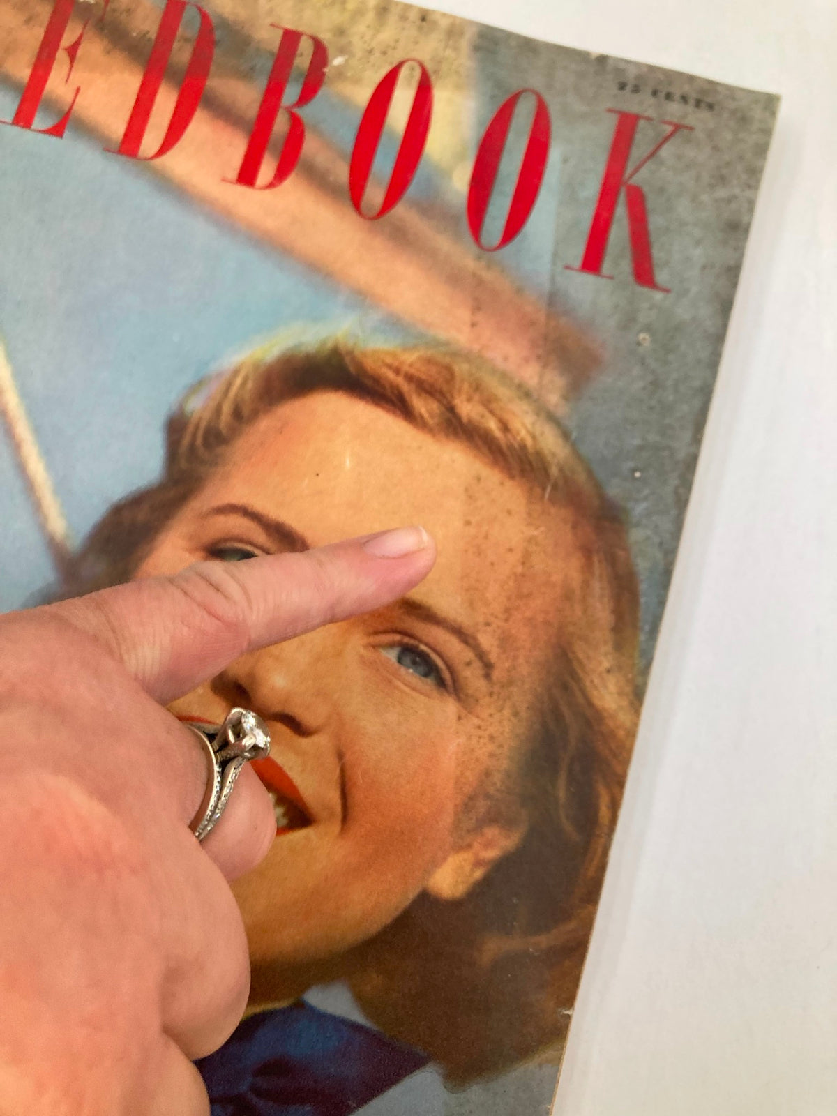 Close-up of the cover of VTG Redbook Magazine May 1949 Vol 93 #1, highlighting a woman's face as she smiles, with a finger pointing to an imperfection on the cover.
