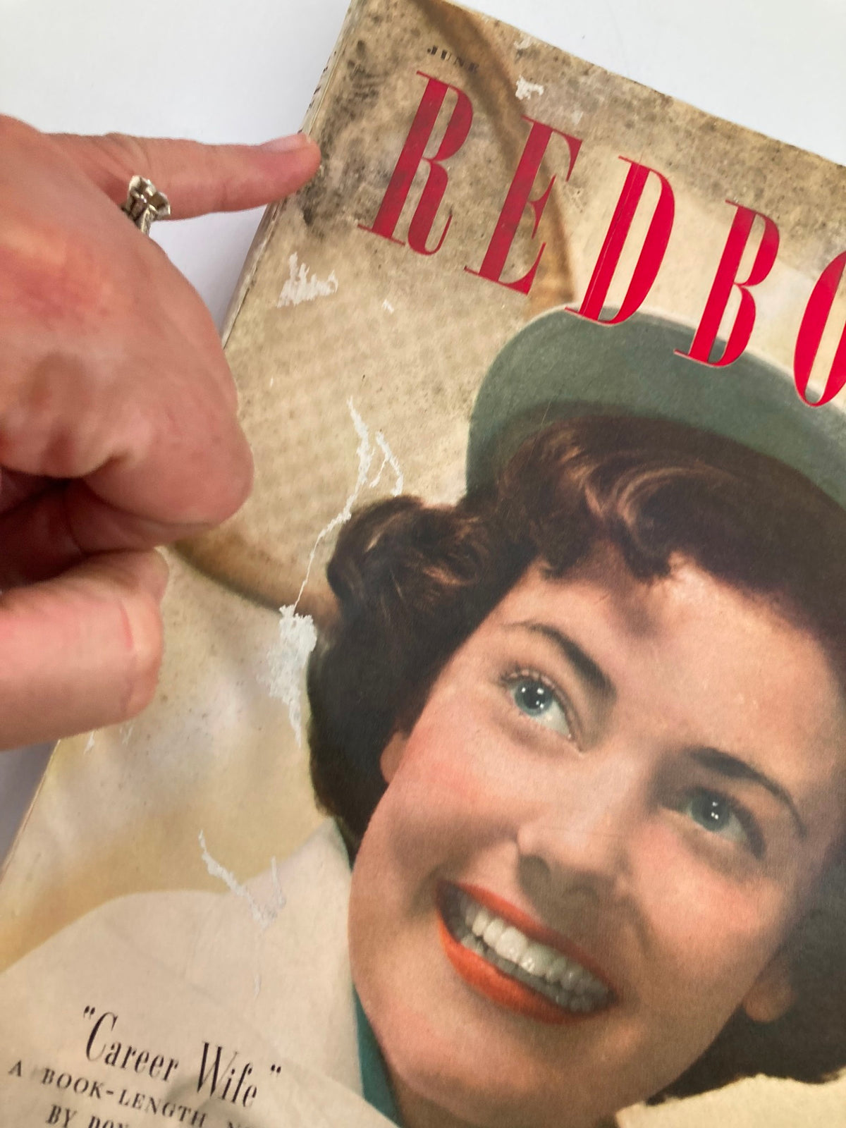 Close-up of the cover of VTG Redbook Magazine June 1949 Volume 93 Issue 2, highlighting signs of wear with a finger pointing at wear marks, featuring the title 'Career Wife'.
