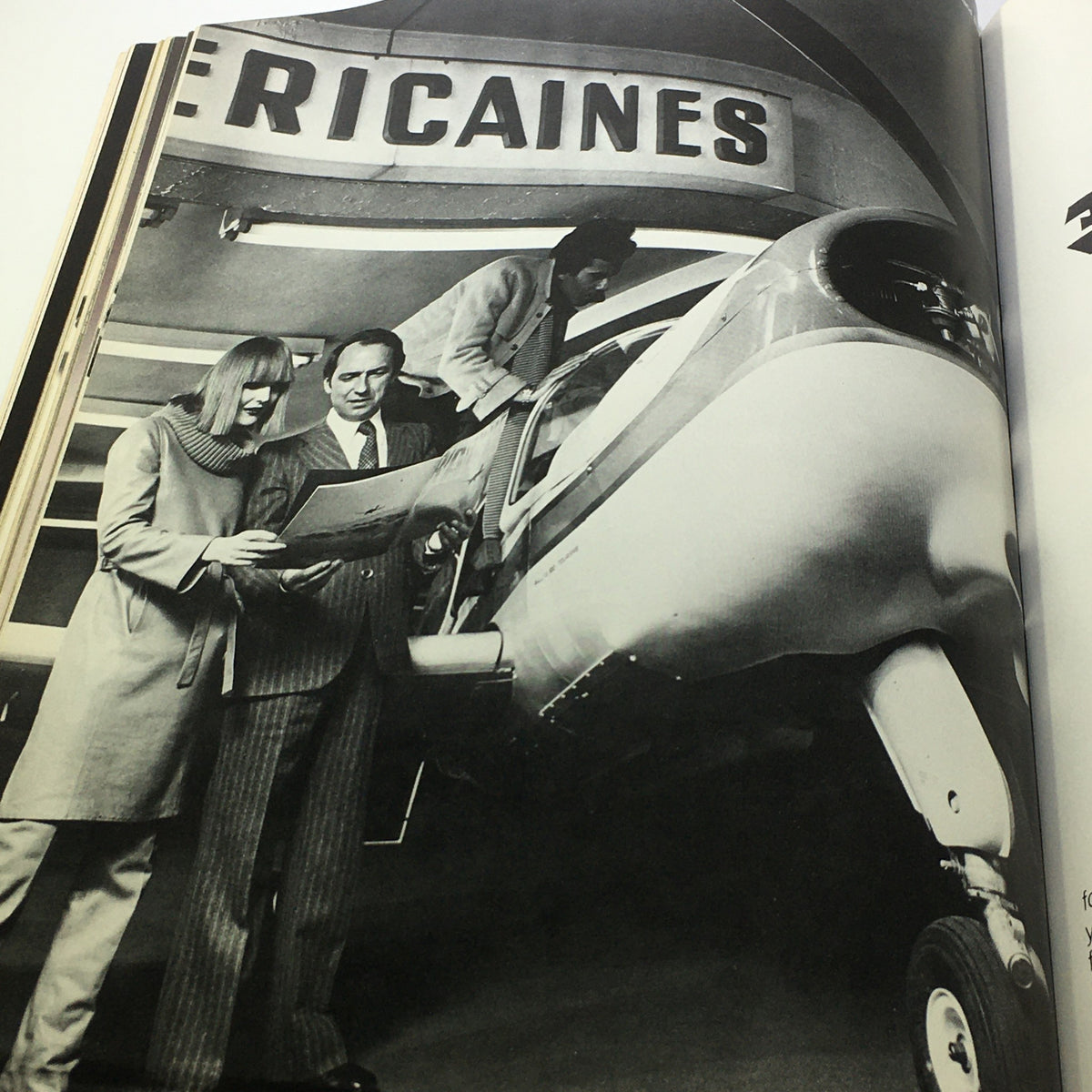 L'Officiel USA Magazine Fall Collection 1976 capturing a moment of three individuals discussing fashion while near an airplane, highlighting the era's travel and style.