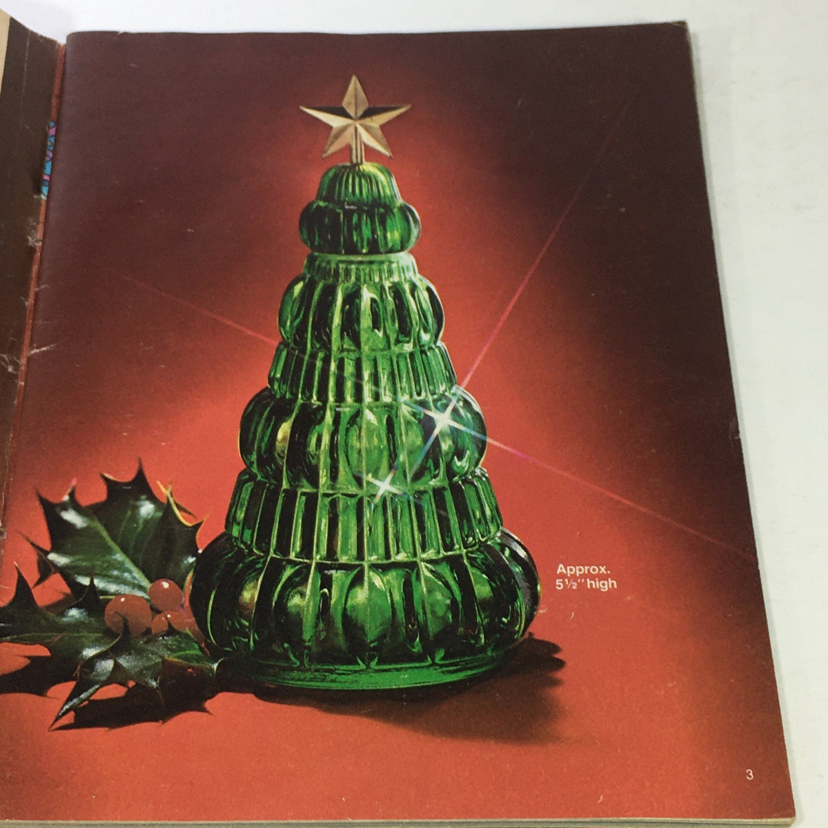 Interior page of the VTG Avon Christmas Price Guide Product Catalog December 1974 displaying a green glass Christmas tree design, accentuated with holly leaves.