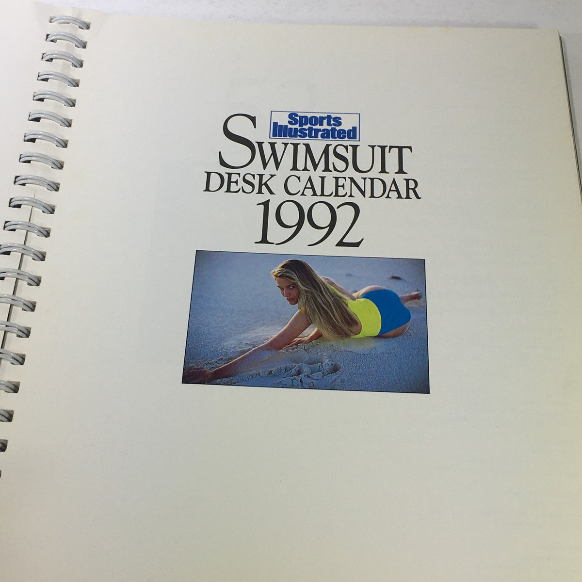 Inside page of the Sports Illustrated 1992 Swimsuit Desk Calendar showing a model lying on the sand in a vibrant swimsuit.