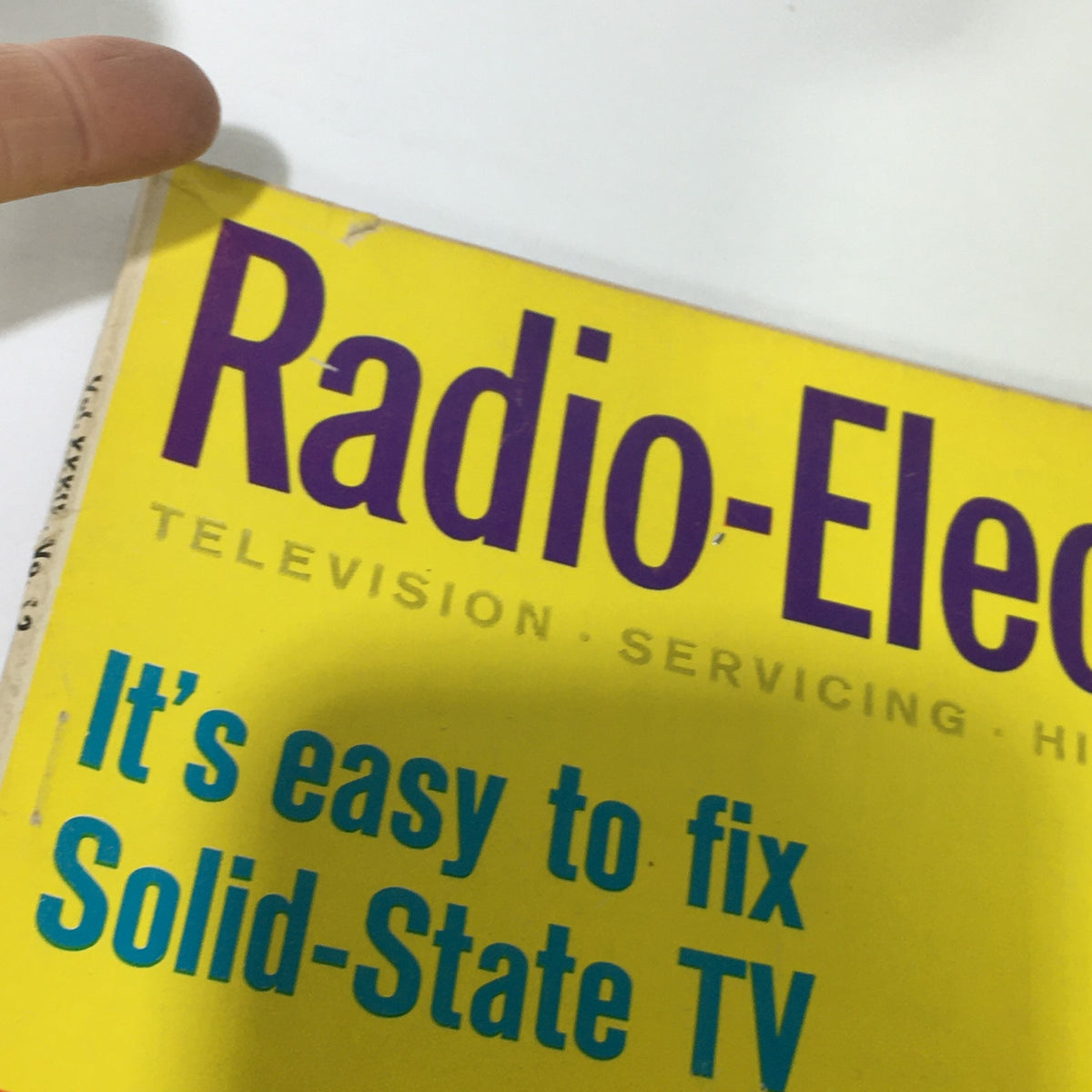 Close-up view of the cover of VTG Radio-Electronics Magazine December 1968, highlighting the title and details about fixing solid-state TVs, accompanied by a finger pointing at the top of the magazine.