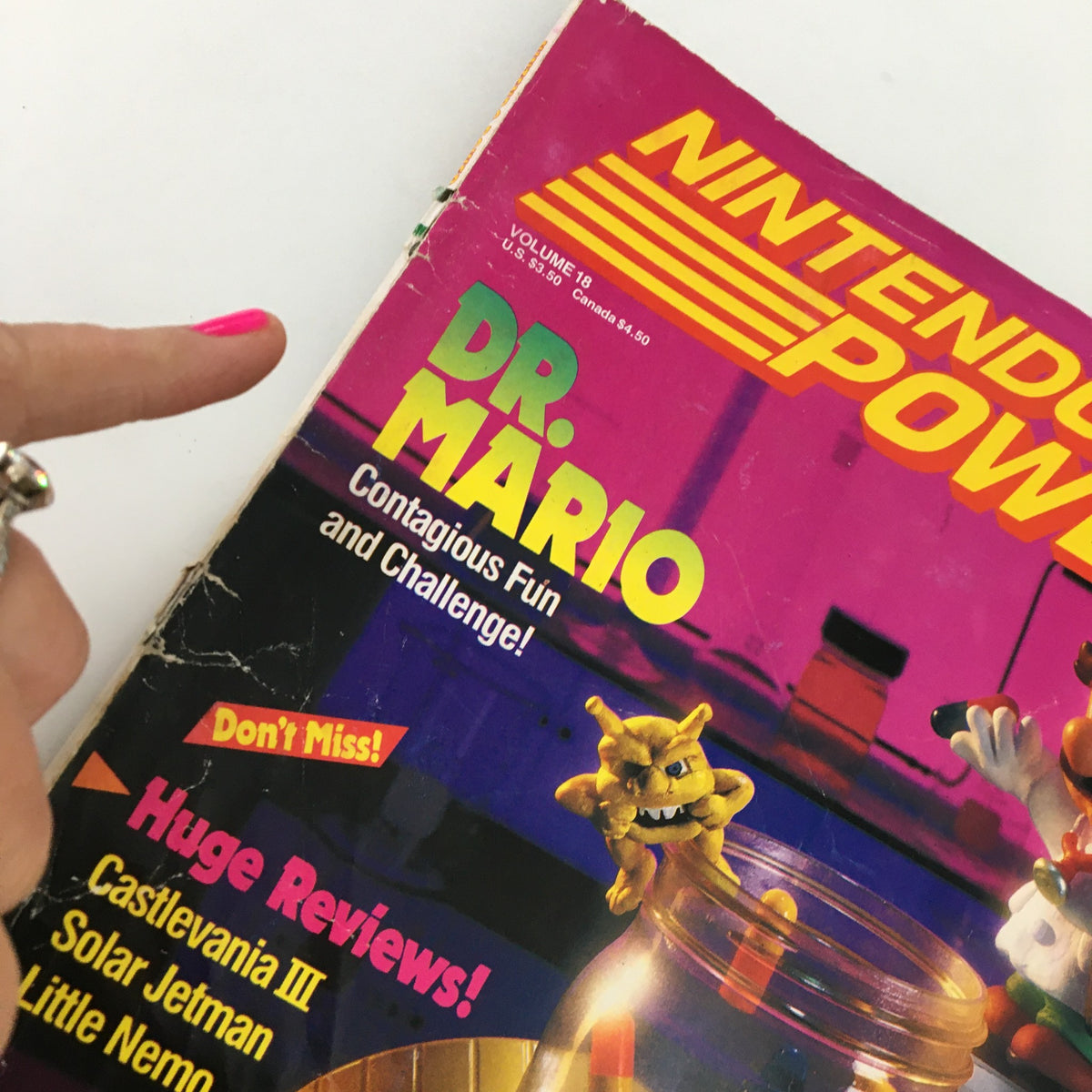 Close-up of the upper section of Nintendo Power Magazine November 1990 #18, focused on the Dr. Mario title with additional elements like colorful pills.