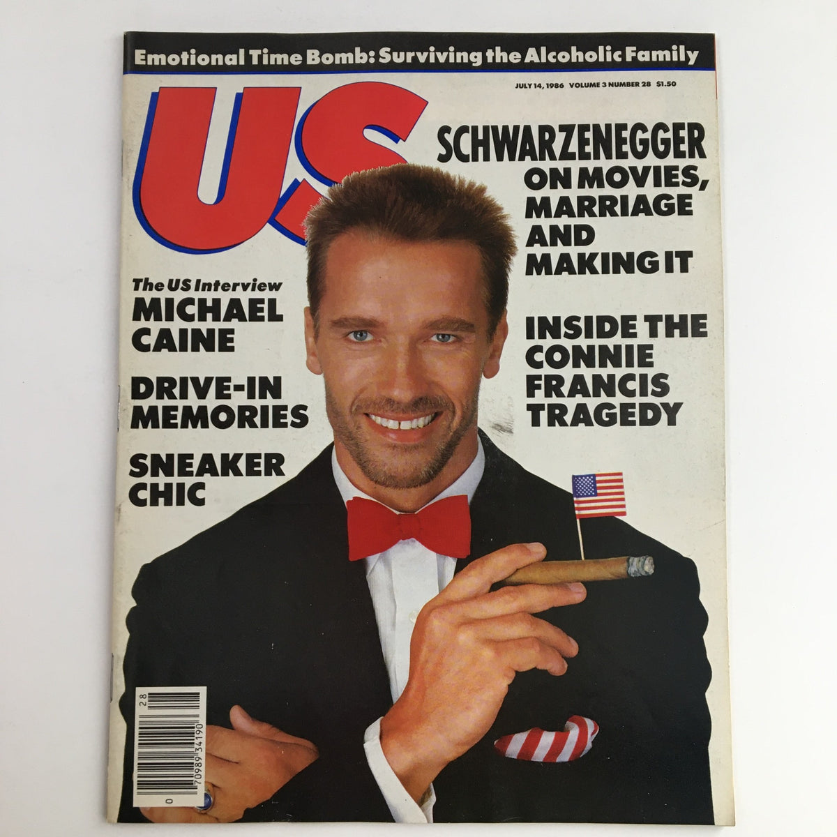 Cover of US Magazine July 14, 1986 featuring Arnold Schwarzenegger smiling with a cigar and wearing a bow tie, alongside the headline 'The US Interview: Michael Caine'. This vintage magazine captures the glamour of the 1980s, making it a collectible item for fans of pop culture.