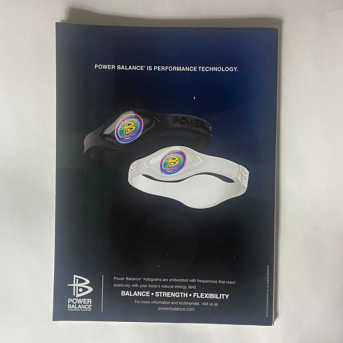 Power Balance advertisement showcasing performance technology wristbands in black and white, emphasizing balance, strength, and flexibility.