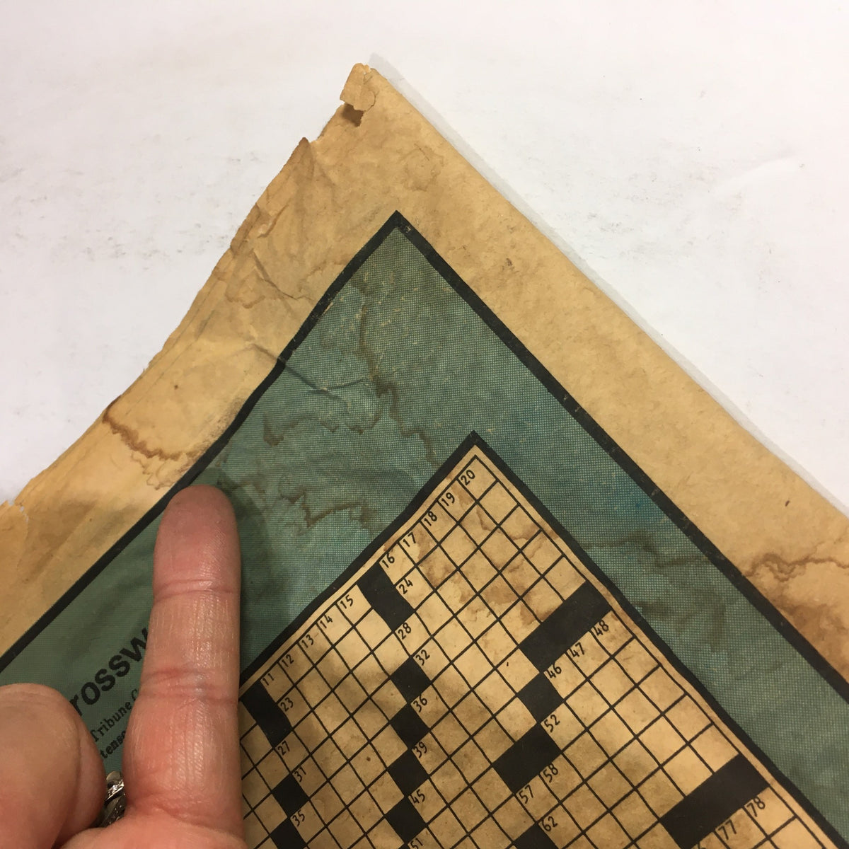 Close-up of the frayed edge of The Sunday Daily Record dated December 28, 1975, featuring the crossword puzzle section, highlighting its vintage condition related to the Karen Anne Quinlan court case.