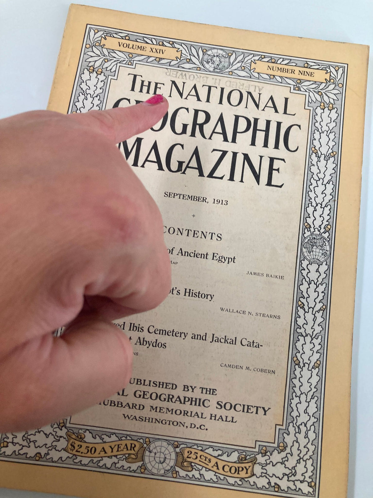 Close-up of The National Geographic Magazine September 1913 cover with a hand pointing at the title, highlighting The Sacred Ibis Cemetery.