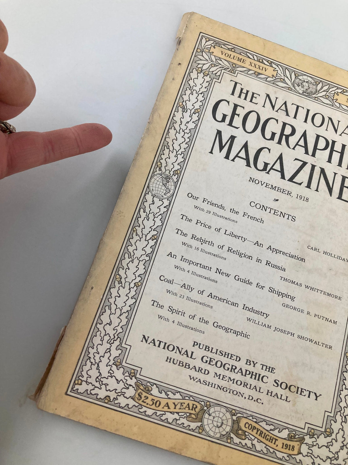 Close-up of the cover of the November 1918 National Geographic Magazine 'Our Friends, The French', with a finger pointing to the contents section.
