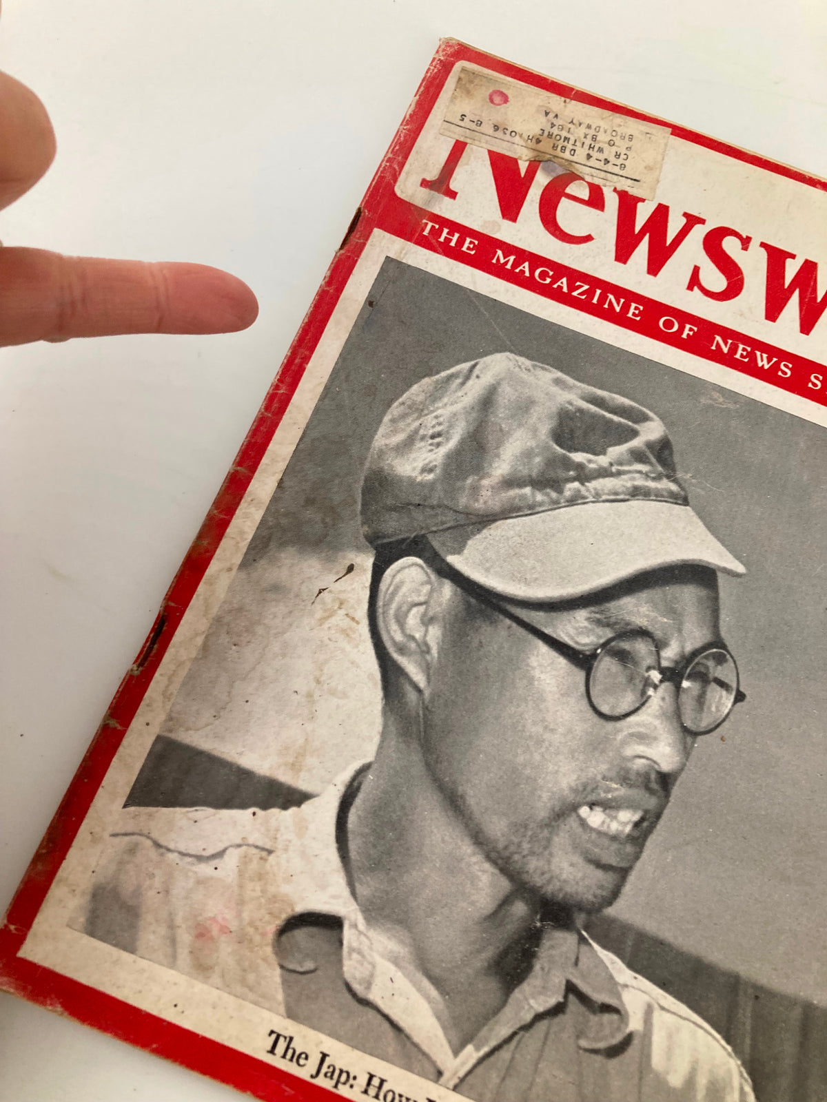 Close-up of the cover of the vintage Newsweek magazine dated July 30, 1945, featuring the title 'The Jap: How Long Can He Take It?' The image shows a man with glasses and a cap, prominently displayed on the cover, alongside visible wear and a label indicative of its age.
