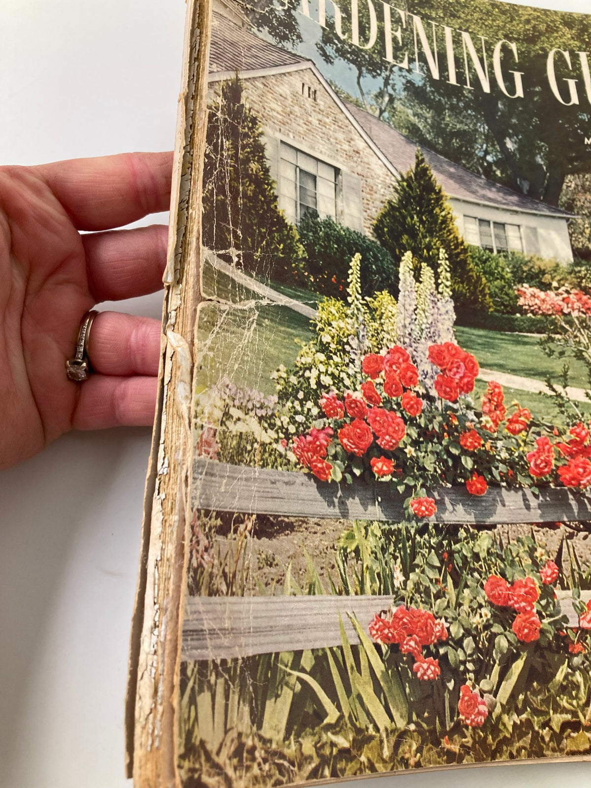 Side view of the VTG Better Homes & Gardens Gardening Guide 1951, highlighting its weathered condition and flowering plants on the cover.