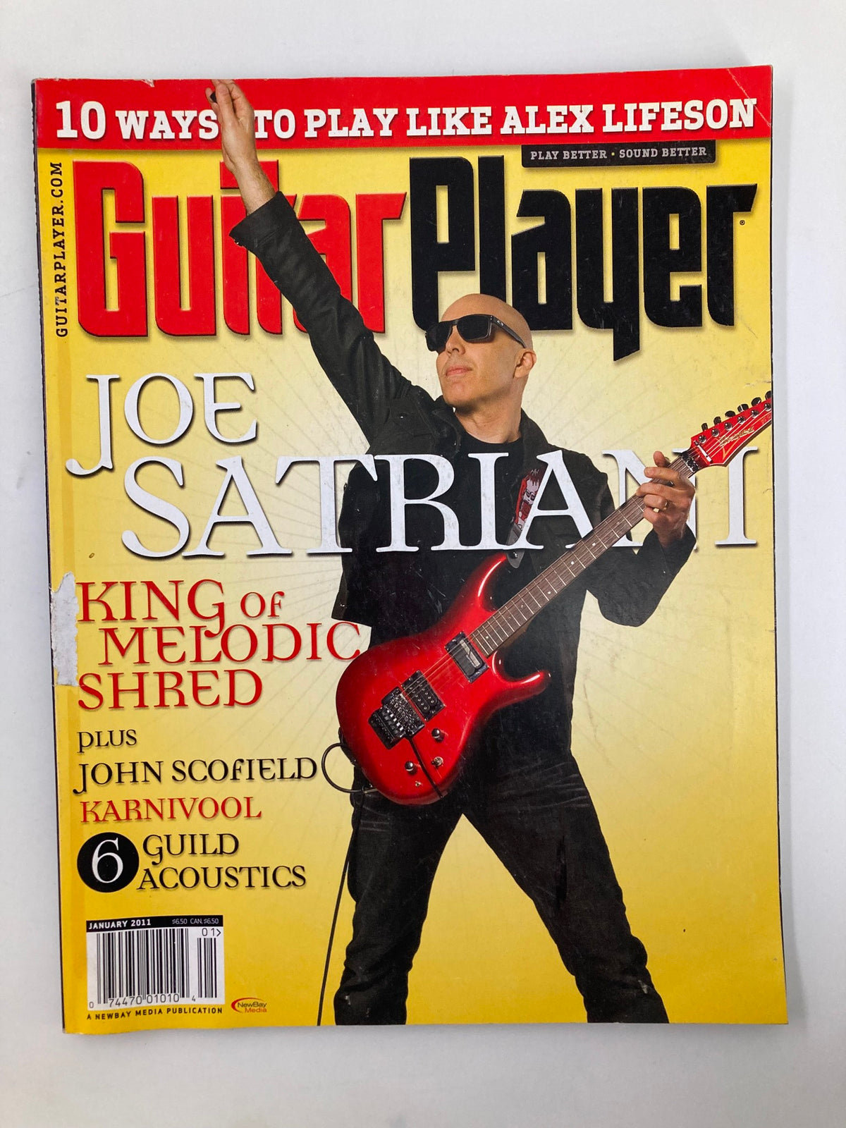 Cover of Guitar Player Magazine January 2011 featuring Joe Satriani, the King of Melodic Shred, showcasing his iconic red guitar against a vibrant yellow background.