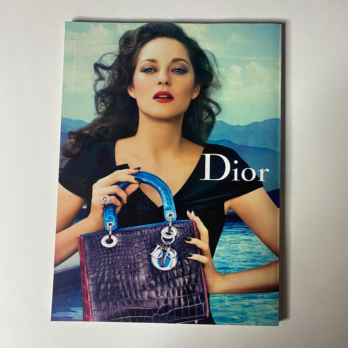 Vogue Magazine February 2012 Taylor Swift Cover No Label VG displaying a Dior advertisement with a glamorous model holding a designer handbag, set against a scenic backdrop.