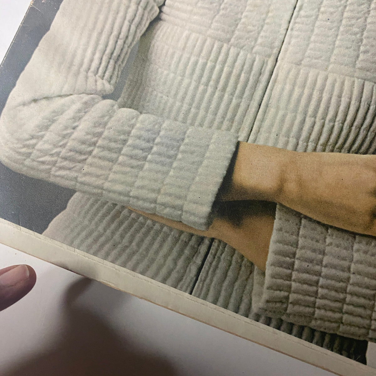 Close-up detail of a quilted vinyl jumpsuit from Harper's Bazaar Magazine May 1966, showcasing the textured fabric and arm design, highlighting the avant-garde fashion of the era.