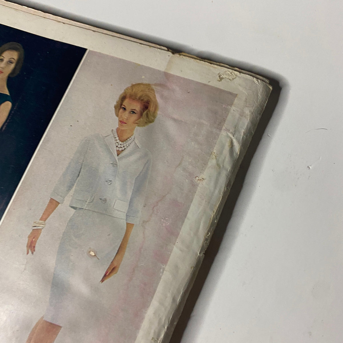 Cover detail of Harper's Bazaar Magazine April 1961 featuring a model in a chic white suit and pearls, showcasing early '60s fashion styles as part of the issue titled 'Under All: Blue Roses'.