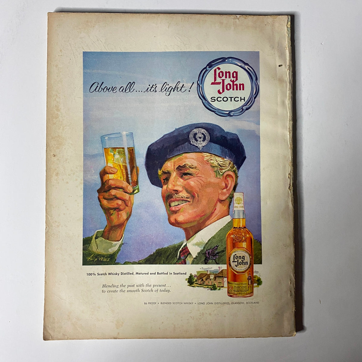Back cover advertisement for Long John Scotch, featuring a man in a beret holding a glass of whisky, set against a rustic background. This vintage ad emphasizes the lightness and quality of Long John Scotch, reflecting the branding of the product.