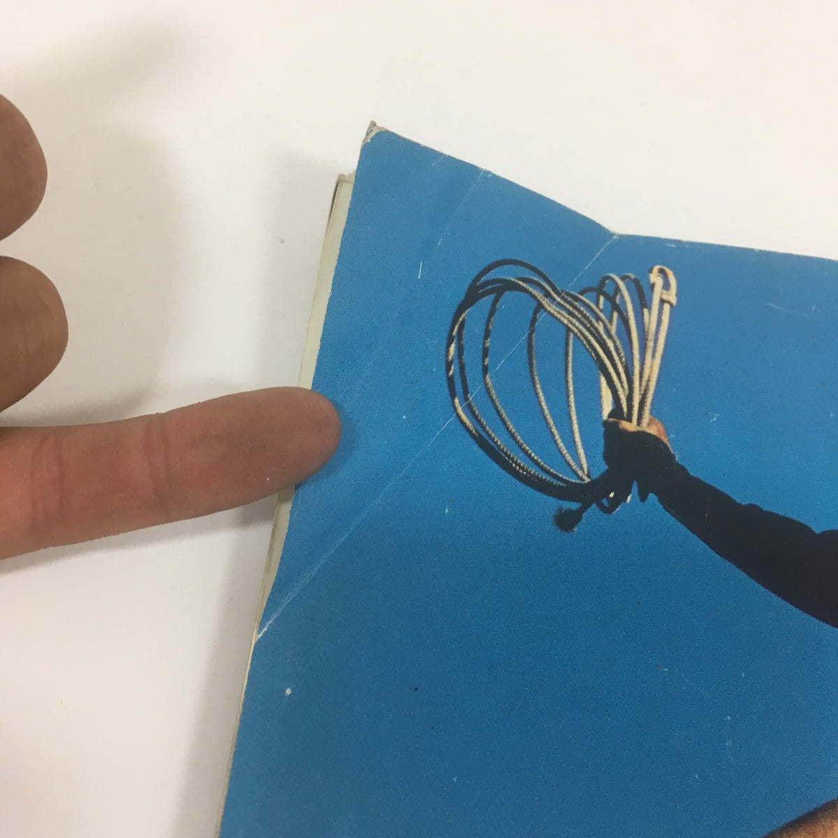 Close-up of the cover of the Official Super Bowl XXV Game Program, featuring a hand pointing at the spine of the magazine, showcasing its good condition.
