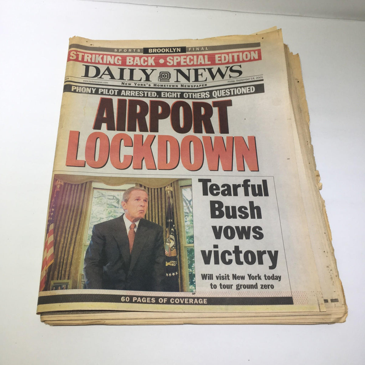 NY Daily News front page from September 14, 2001, featuring the headline 'Airport Lockdown' with a photo of a tearful President Bush vowing victory, highlighting the events surrounding the 9/11 attacks.