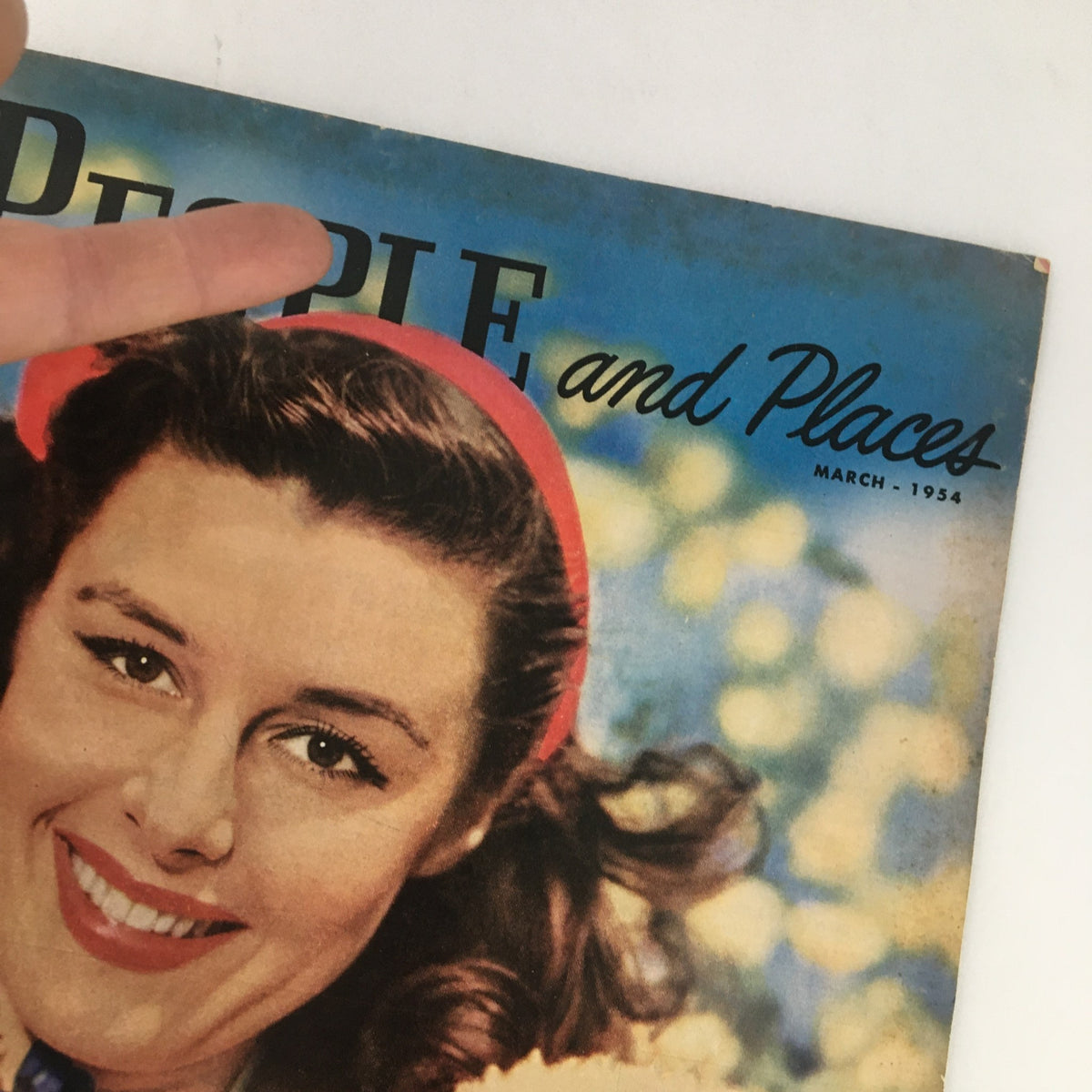 Cover image of People and Places Magazine from March 1954 featuring a smiling lady with a lamb, reflecting vintage charm and nostalgia.