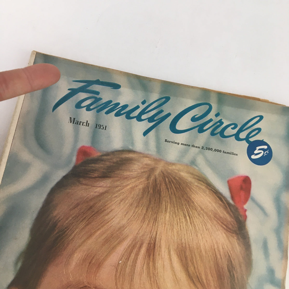 Close-up of the top section of the Family Circle Magazine cover from March 1951 displaying the title and date, with a child's portrait and a playful red ribbon.