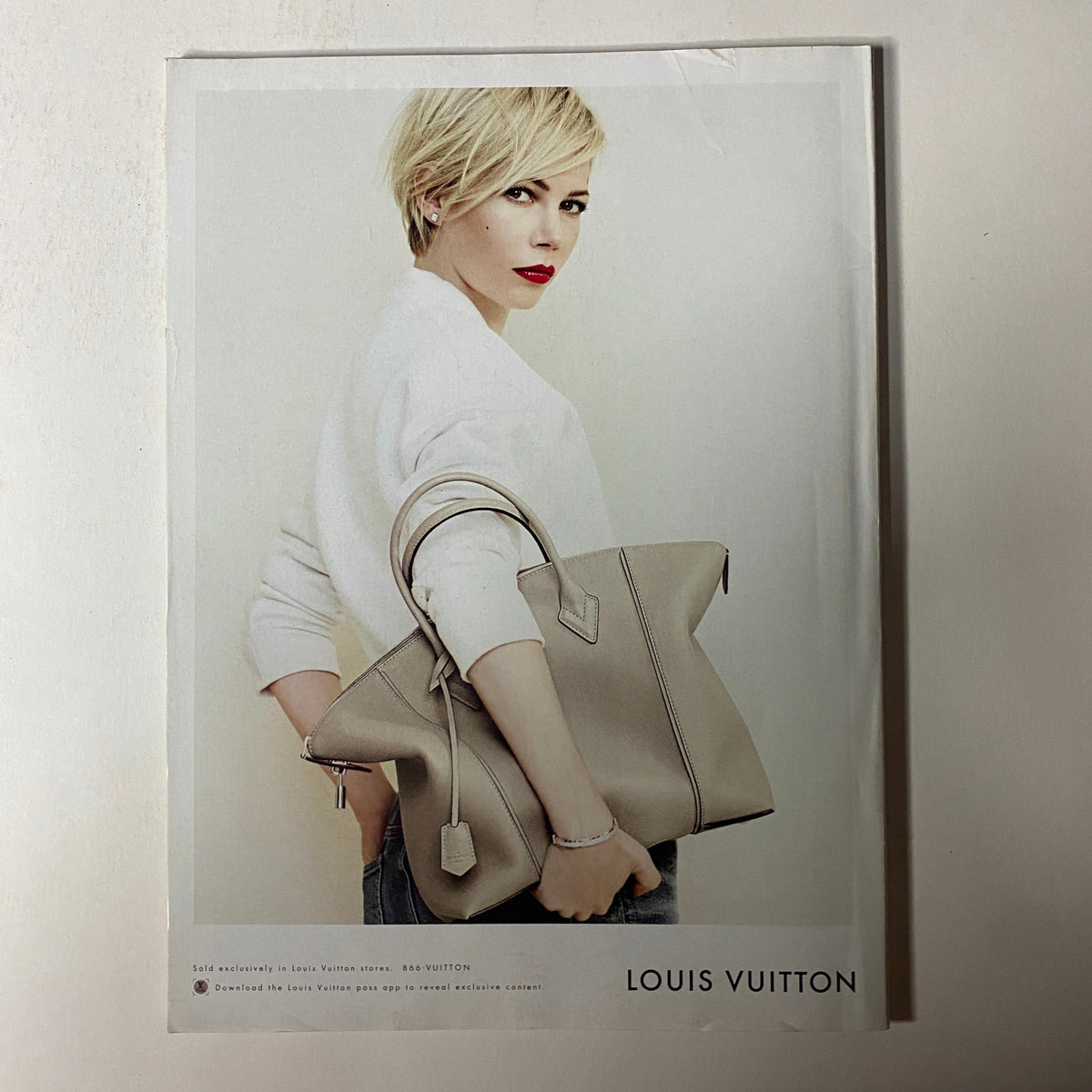 Advertisement from Vogue Magazine July 2014 featuring a model with a stylish Louis Vuitton bag, emphasizing contemporary luxury fashion.