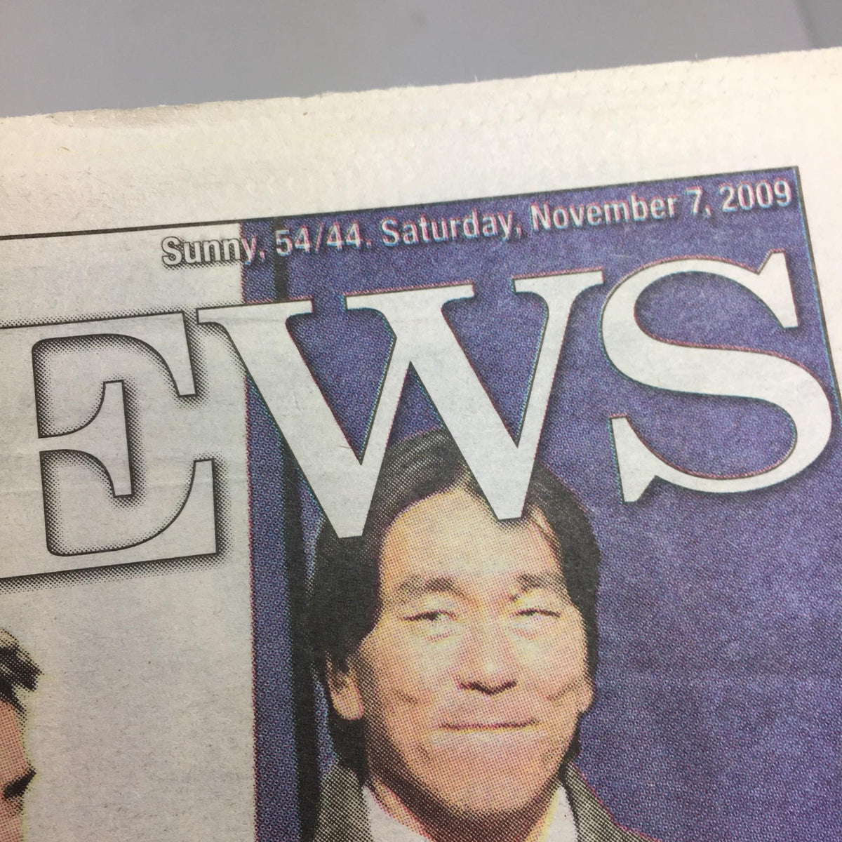 Close-up of the New York Daily News headline on November 7, 2009, showing the date and weather report along with a smiling individual.