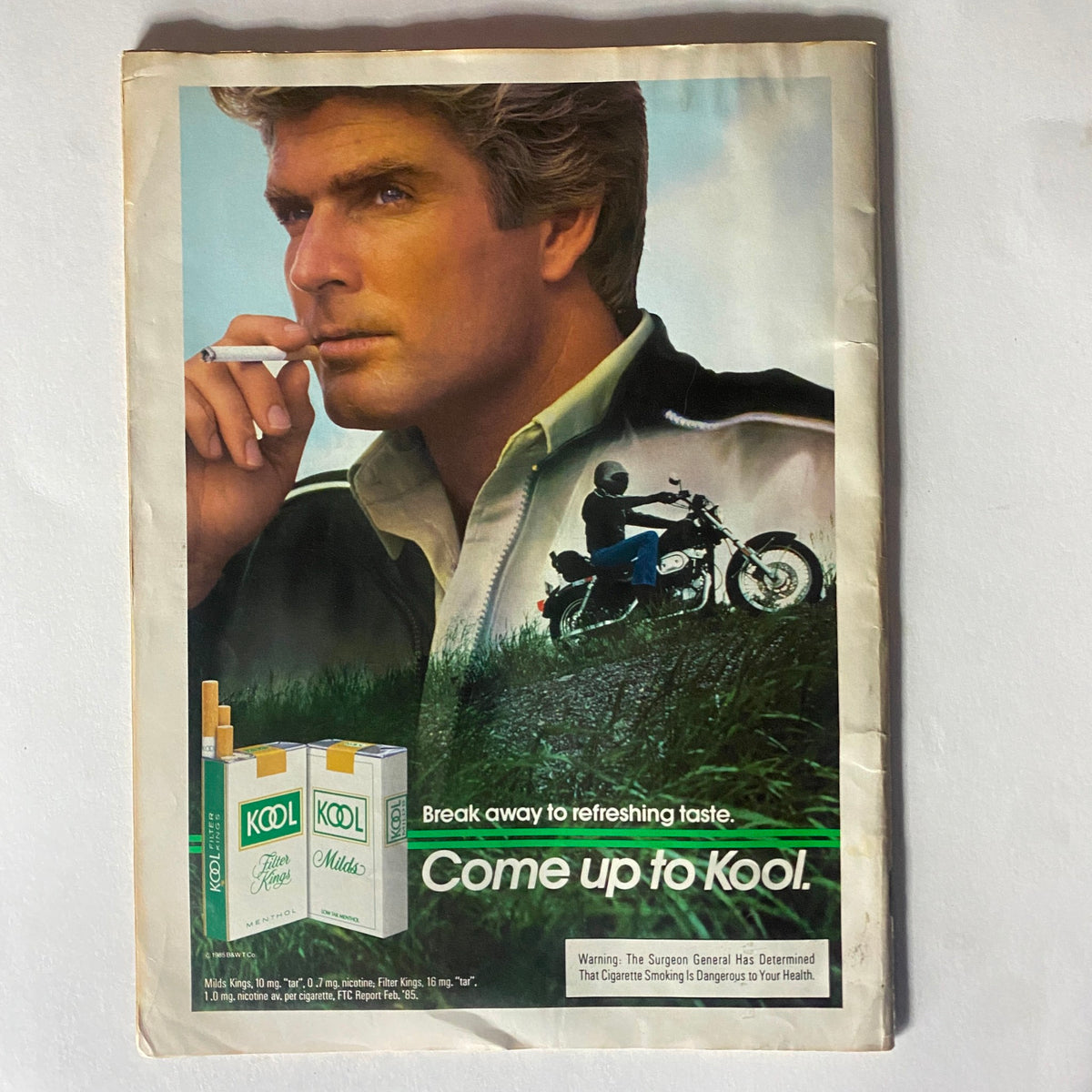 Vintage advertisement from VTG Record Magazine July 1985, promoting Kool cigarettes, featuring a suave model and a motorcycle, highlighting lifestyle imagery of the 1980s.