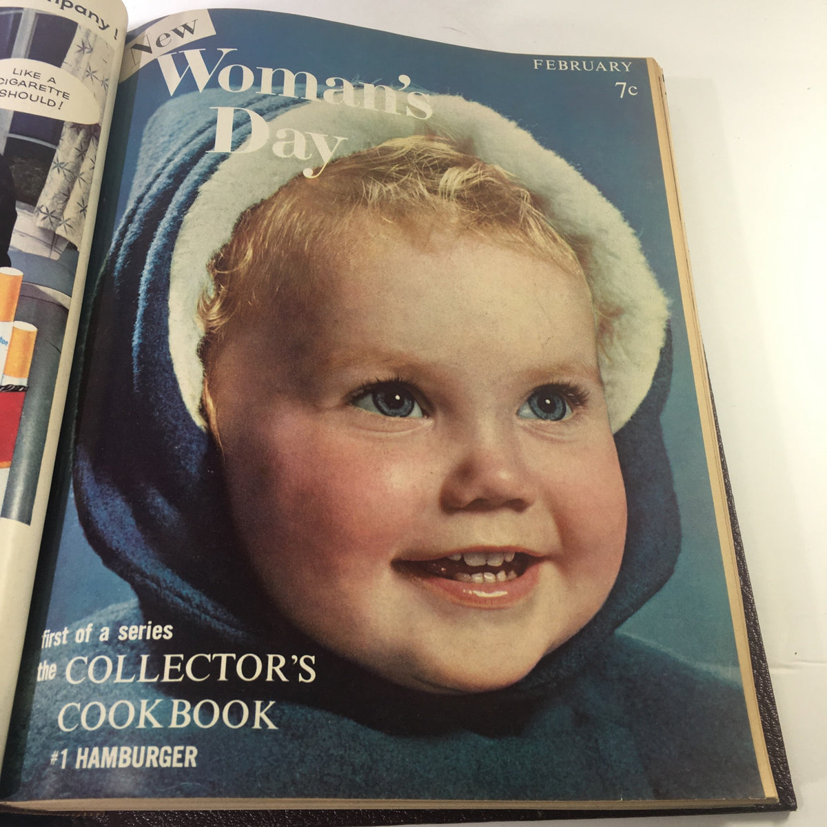 February 1957 cover of Woman's Day Magazine with a smiling young girl in a blue hood, introducing the Collector's Cookbook series.