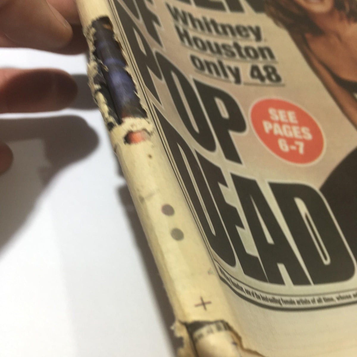 Side view of the New York Post newspaper dated February 12, 2012, displaying the headline 'Queen of Pop Dead' and page number indicators for further reading.