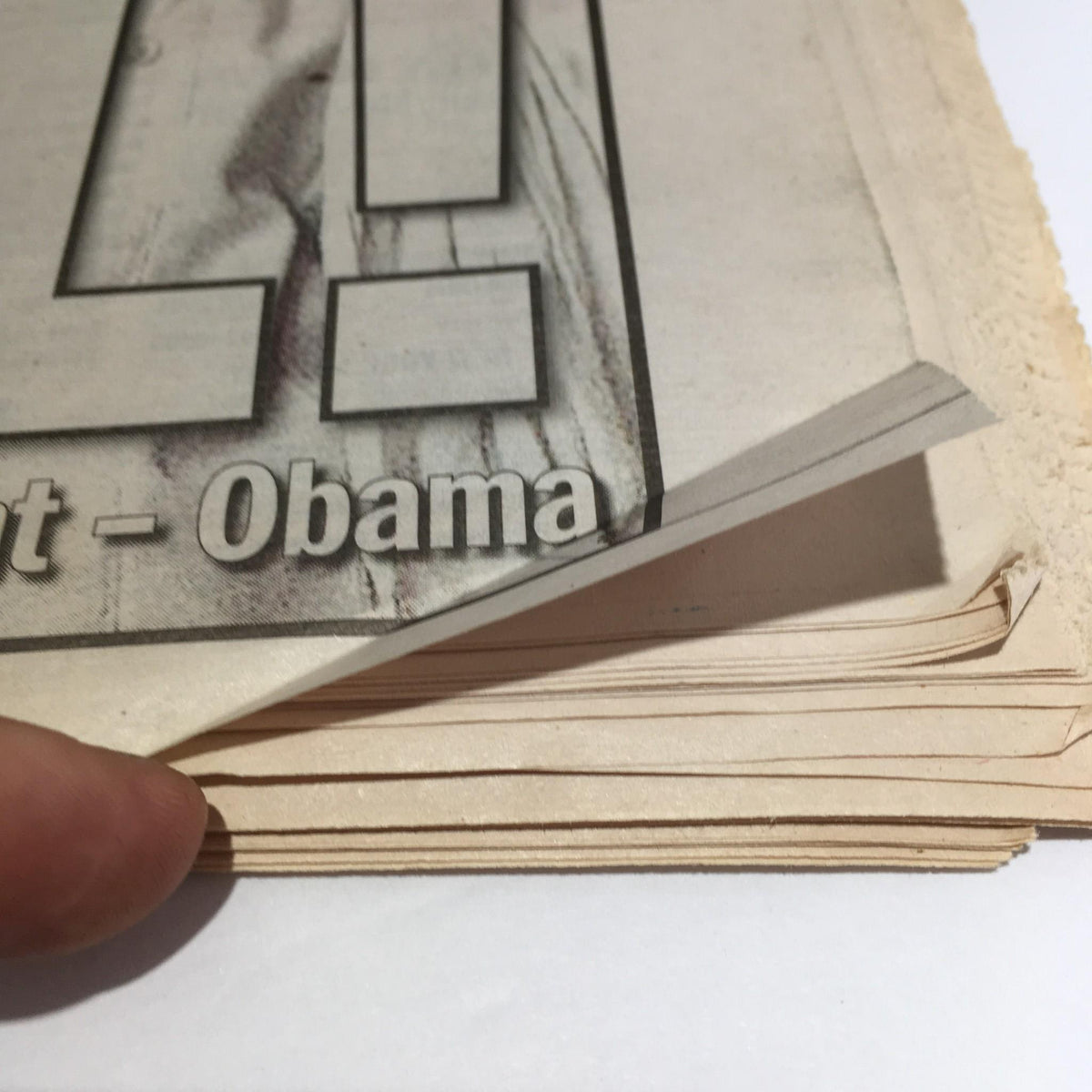 Interior view of NY Daily News magazine from May 2, 2011, showing the edge of the pages with a finger pointing to the text 'Rot in Hell! U.S. team kills Bin Laden in firefight'.