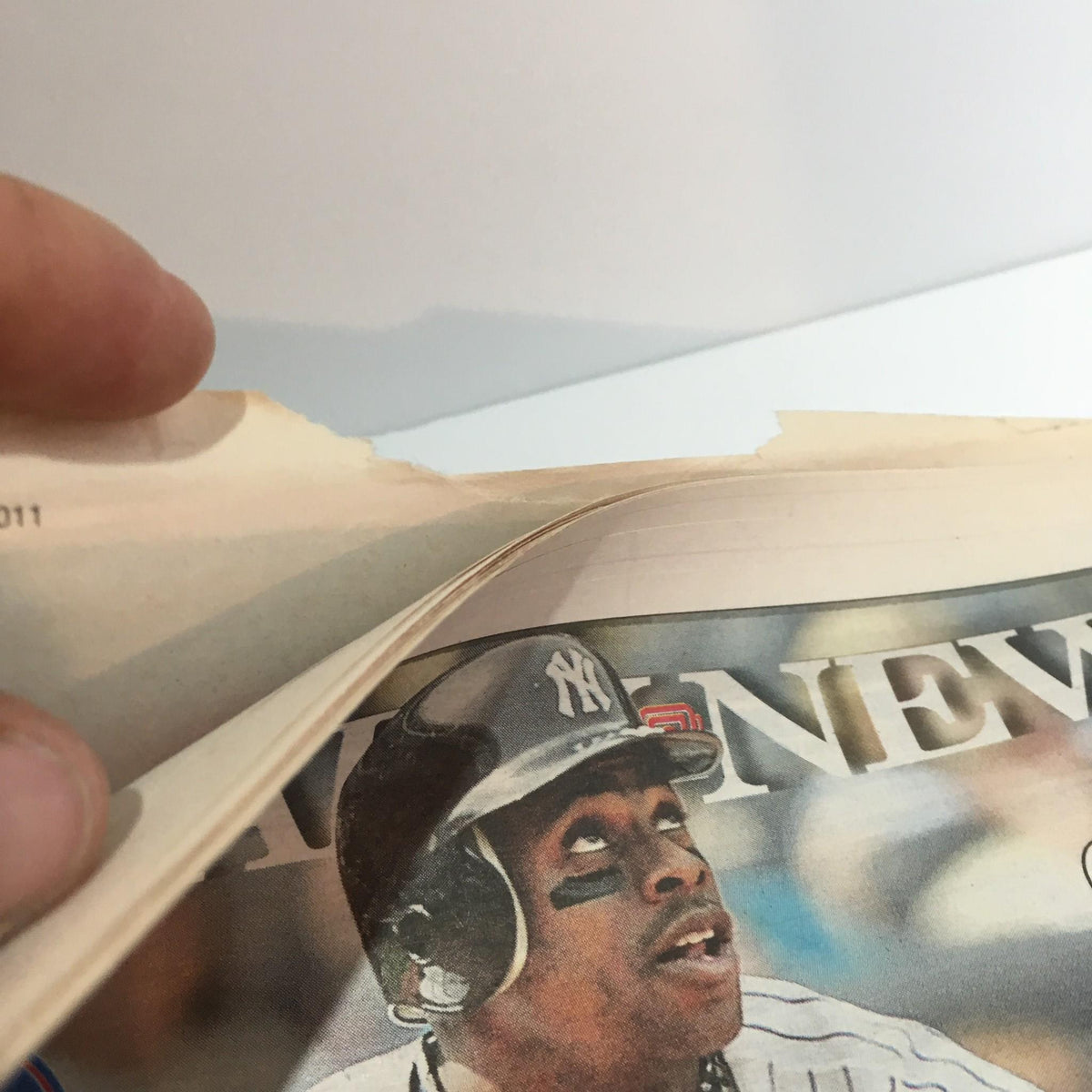 Detail of NY Daily News from May 2, 2011, showing chipped edges and an athlete, highlighting the vintage condition of the magazine titled 'Rot in Hell: U.S. Team Kills Bin Laden in Firefight'.